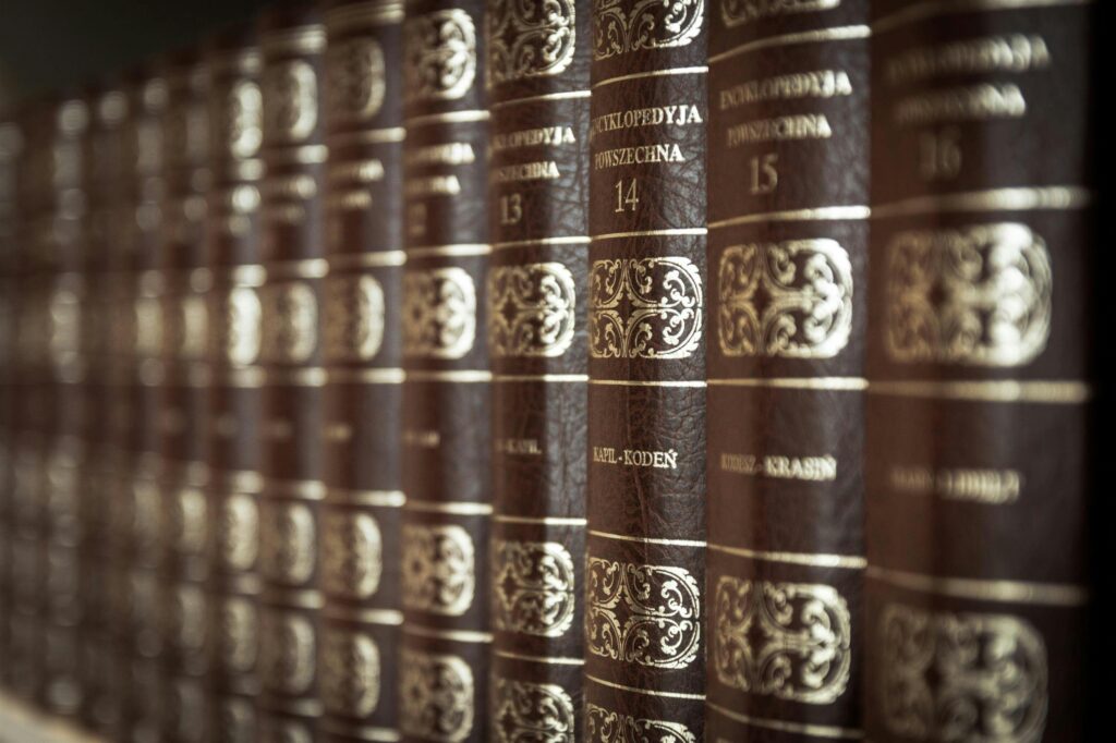 A close-up view of vintage encyclopedias on a library bookshelf, highlighting the ornate leather bindings.